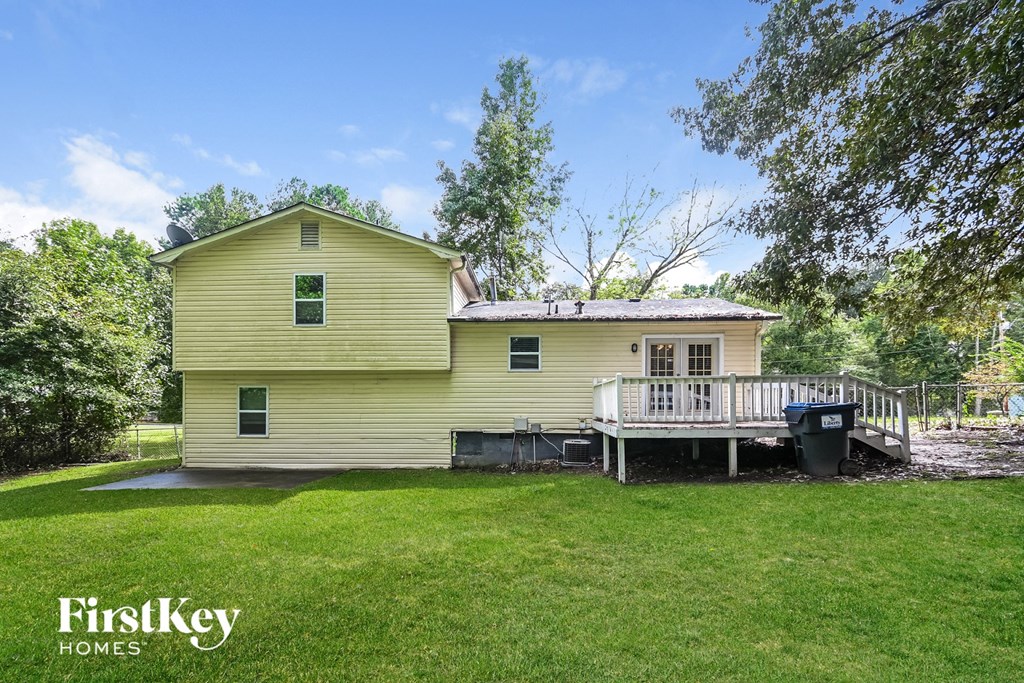 a yellow house with a deck and a large yard