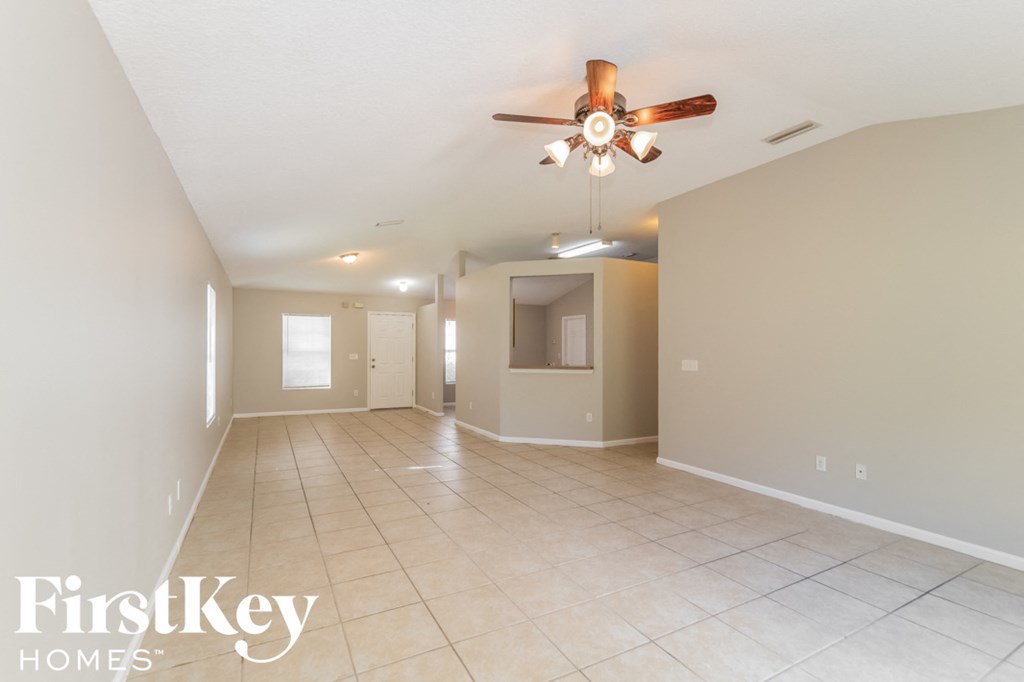 a spacious living room with tile flooring and a ceiling fan
