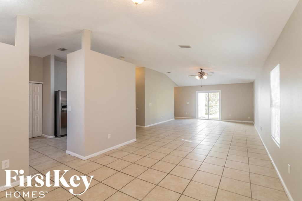 an empty living room with a tile floor and a ceiling fan