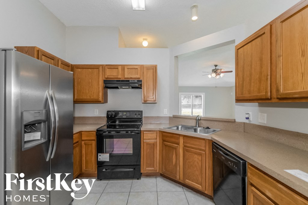a kitchen with wood cabinets and black appliances and stainless steel refrigerator