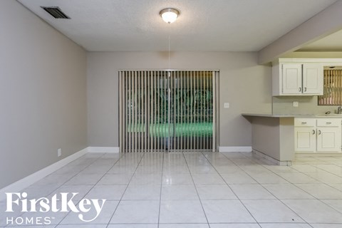 A room with a sliding door and a kitchen area in the background.