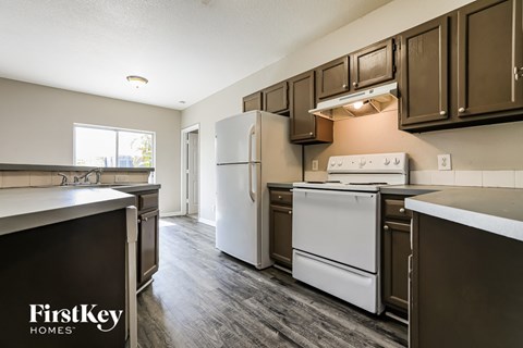 an empty kitchen with white appliances and brown cabinets