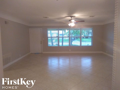 an empty living room with a ceiling fan and a window