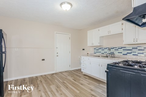 A kitchen with a black stove top oven and white cabinets.