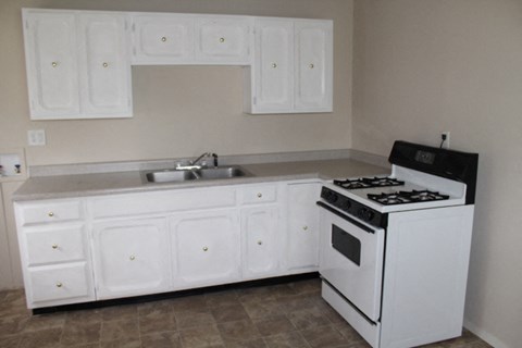 an empty kitchen with white appliances and white cabinets