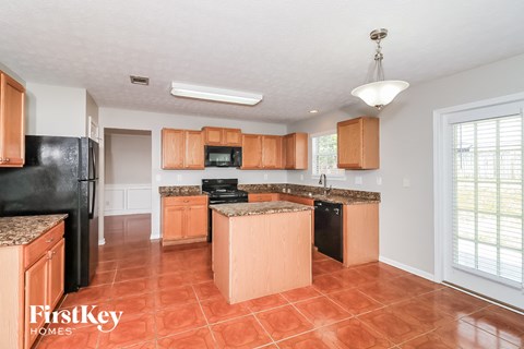 A kitchen with a black fridge and wooden cabinets.