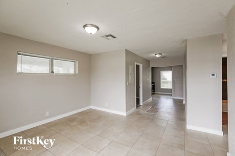 A spacious room with a tile floor and a window with blinds.