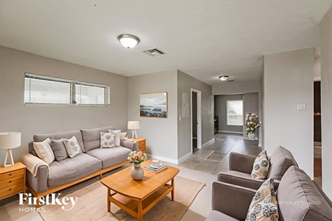 A well-lit living room with a grey sofa, wooden coffee table, and a painting on the wall.