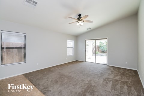 an empty living room with a ceiling fan and a door to a patio