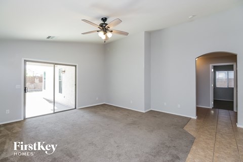 an empty living room with a ceiling fan and a door to a patio