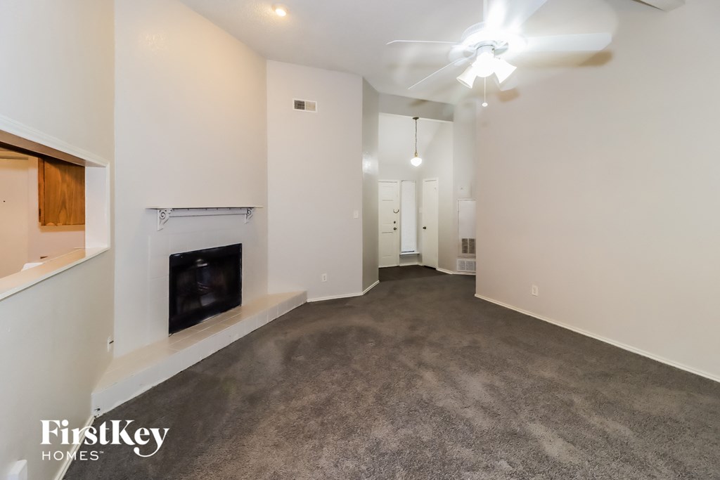 a carpeted living room with a fireplace and white walls