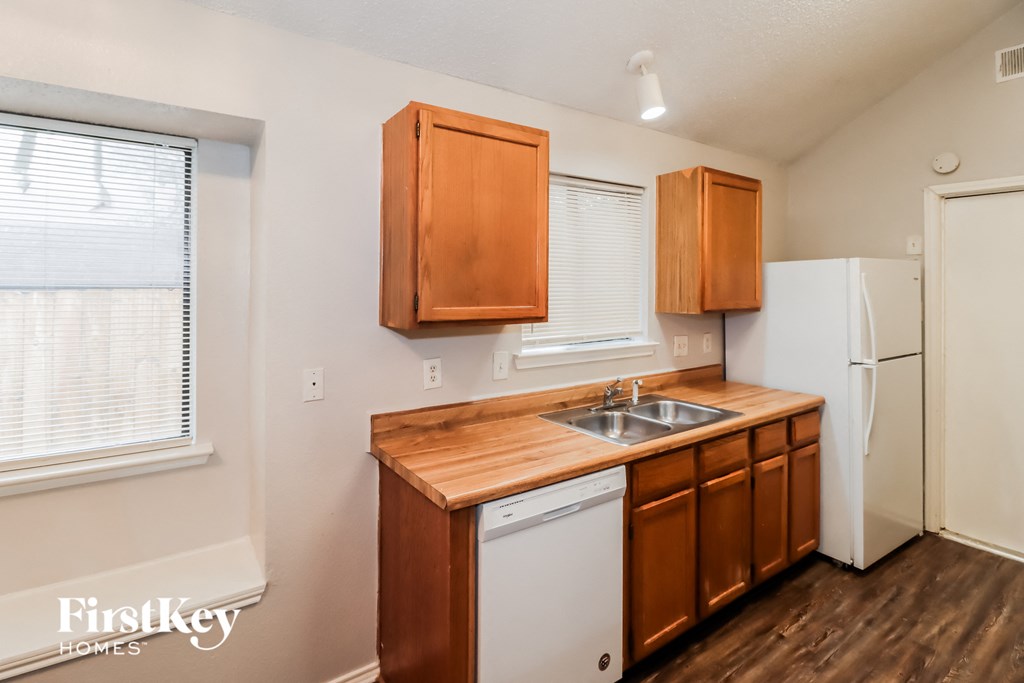 a kitchen with wooden cabinets and a sink and a refrigerator
