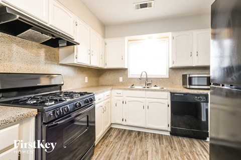 A kitchen with a black stove top oven and white cabinets.
