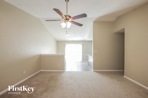 A spacious room with a ceiling fan and carpeted floor.