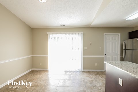 A kitchen with a refrigerator and a window with blinds.