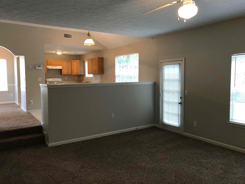an empty living room with an open door to a kitchen