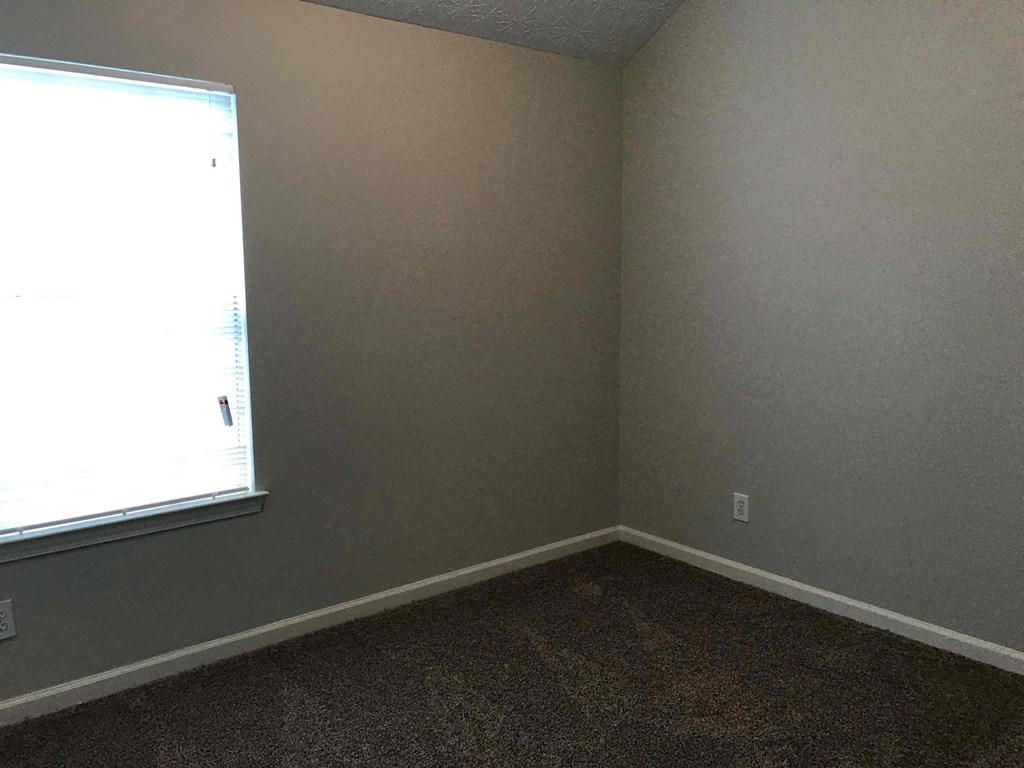 an empty room with a window and a carpet