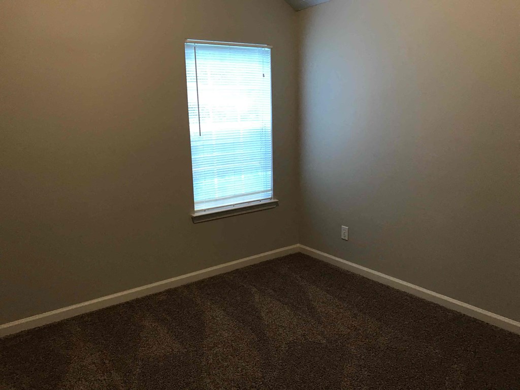 an empty room with a window and carpet