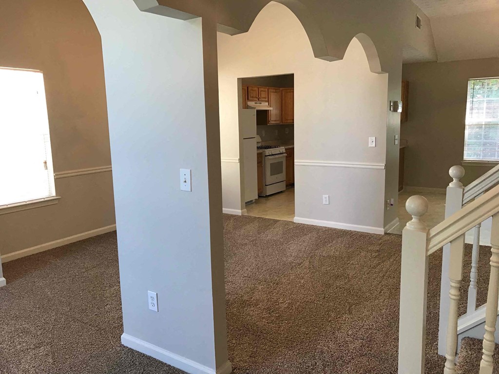 a room with a staircase and a kitchen in a house