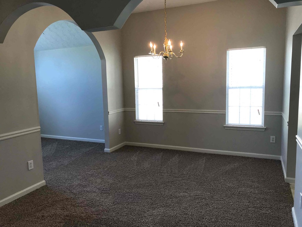 an empty living room with blue walls and a chandelier