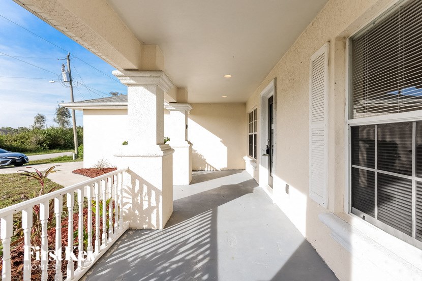a view of the front porch of a house with white pillars and a white railing