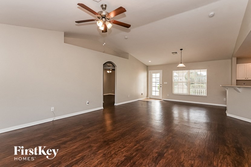 the living room and dining room of an empty house with a ceiling fan