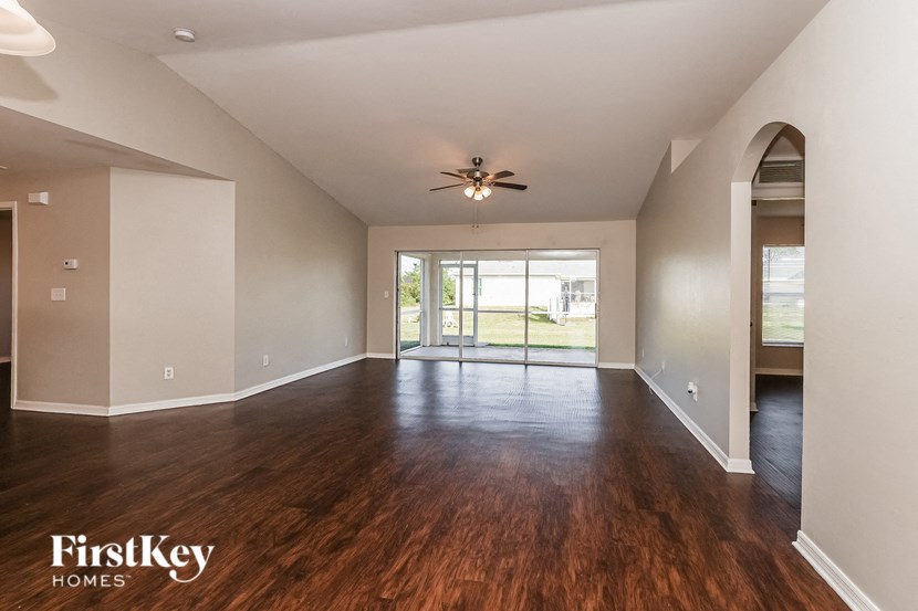 an empty living room with wood flooring and a ceiling fan