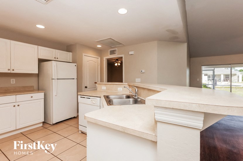 a kitchen with white cabinets and white counter tops and a stainless steel sink