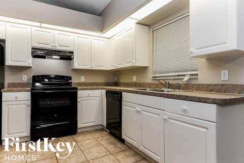 A kitchen with white cabinets and a black oven.