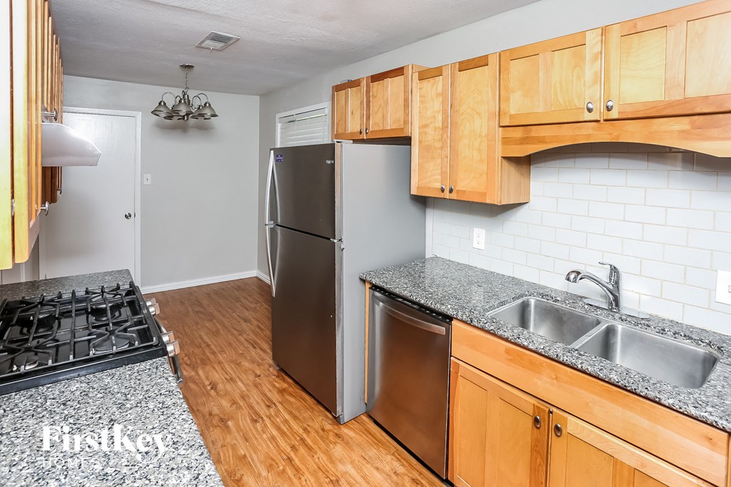 a kitchen with wood cabinets and granite counter tops and a stainless steel refrigerator