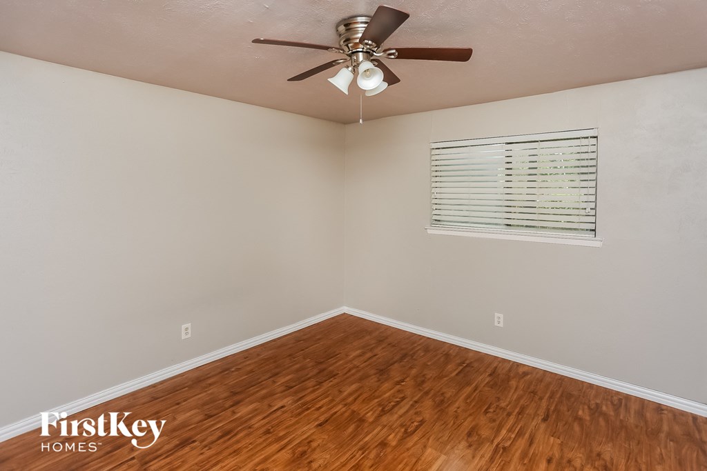 the living room with wood flooring and a ceiling fan