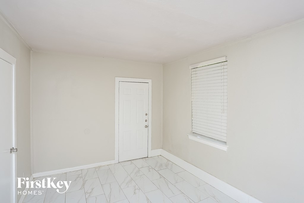 a white room with a door and a window and a white tile floor