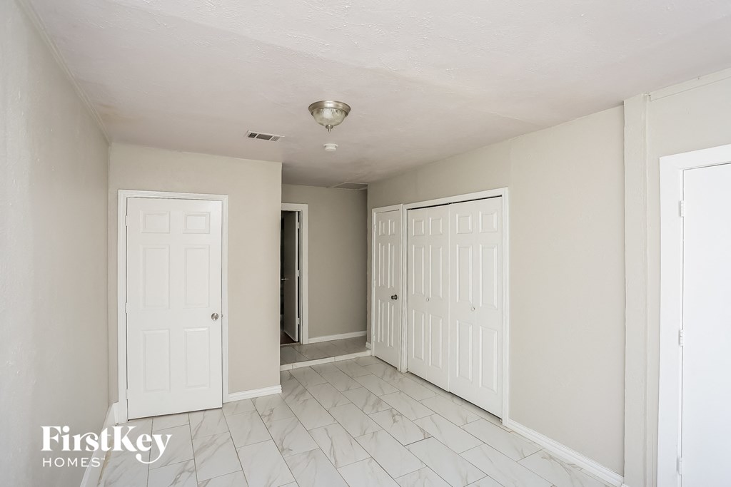 a white hallway with two white doors and a white tiled floor