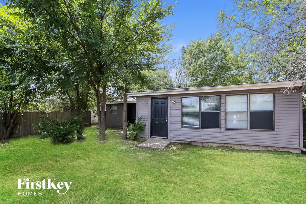 a small pink house with a yard and trees