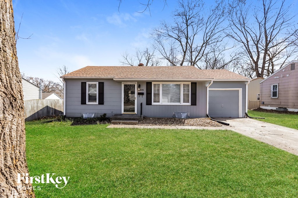 a small gray house with a lawn and a sidewalk