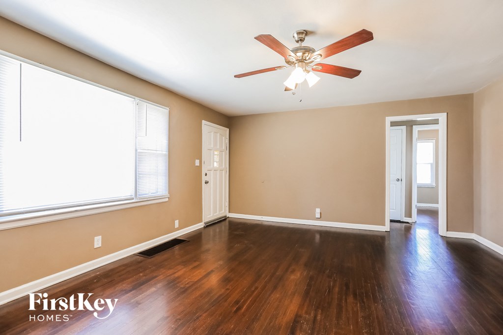 an empty living room with wood floors and a ceiling fan