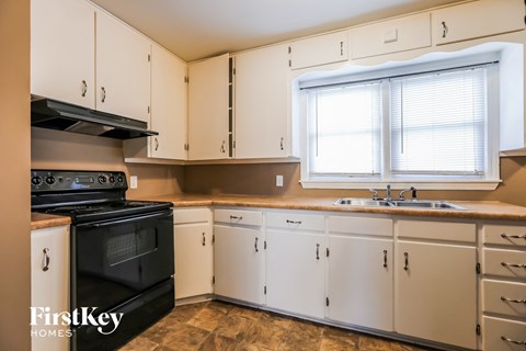 a kitchen with white cabinets and black appliances and a window
