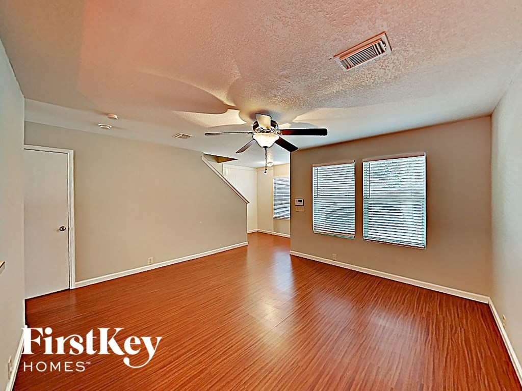 an empty living room with wood floors and a ceiling fan