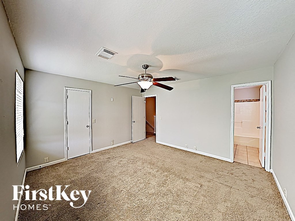 an empty living room with a ceiling fan and a closet