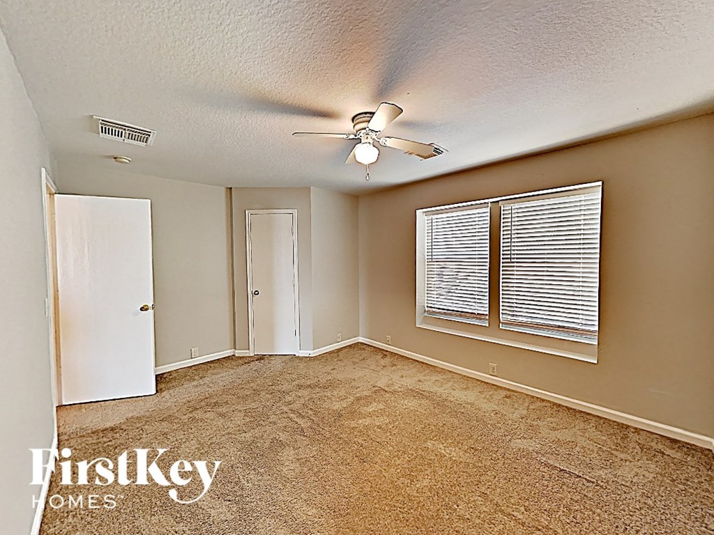 an empty living room with a ceiling fan and a window