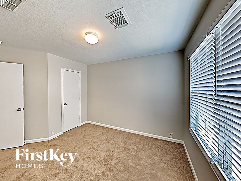 a bedroom with a large window and a carpeted floor