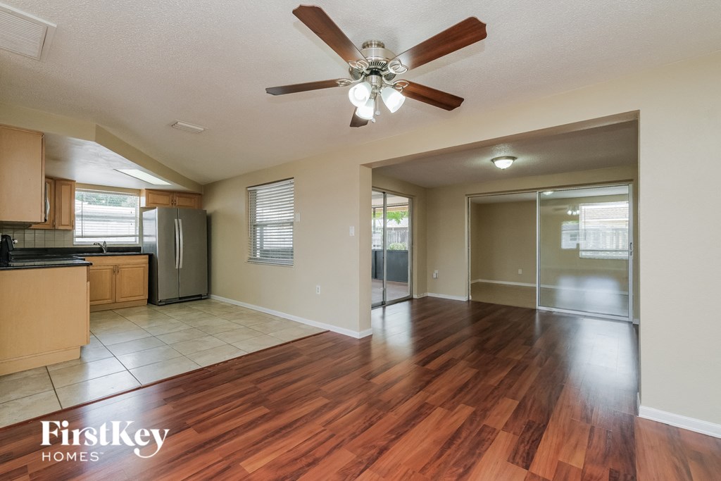 A spacious living room with a wooden floor and a ceiling fan.