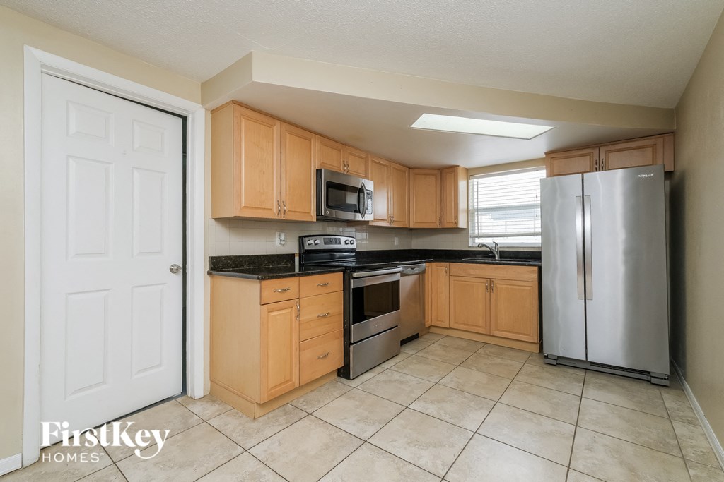 A kitchen with wooden cabinets and a stainless steel refrigerator.