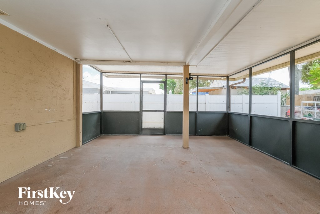 A room with a concrete floor and walls, and a large window with a view of the outside.