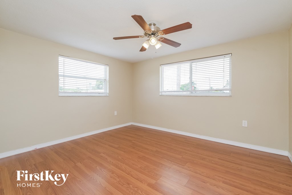 A room with a ceiling fan and wooden flooring.