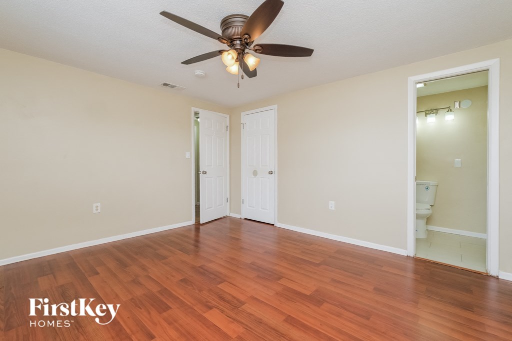 A room with a ceiling fan and wooden floors.