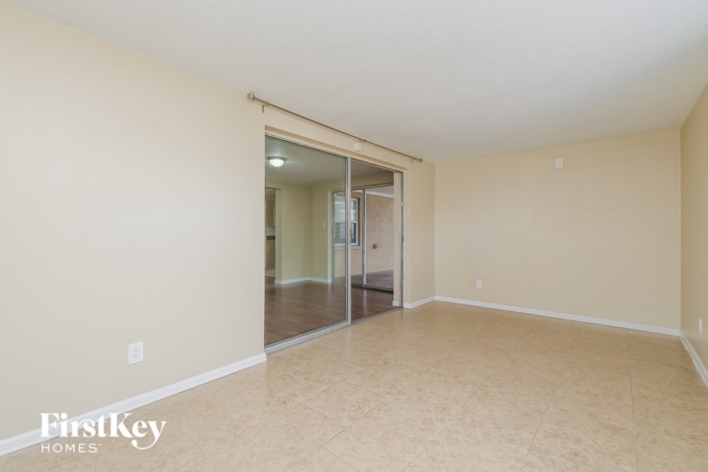 A spacious room with a sliding glass door leading to another room.