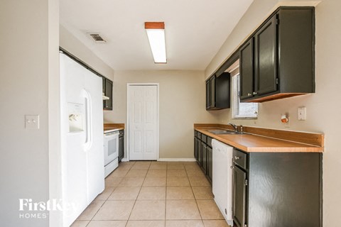 A kitchen with black cabinets and a white refrigerator.
