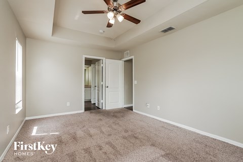 a spacious living room with carpet and a ceiling fan