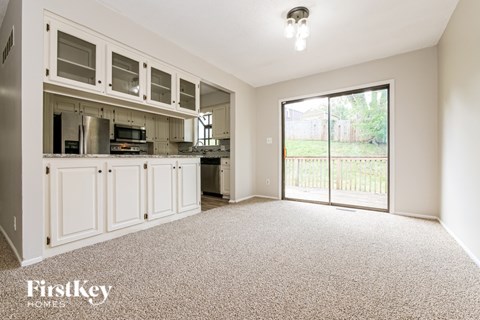 A spacious kitchen with white cabinets and a carpeted floor.
